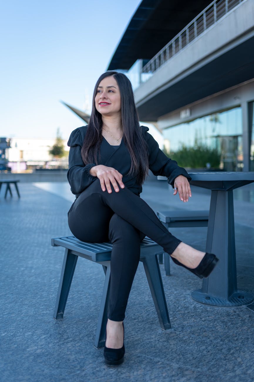 a woman in black pants sitting on a bench