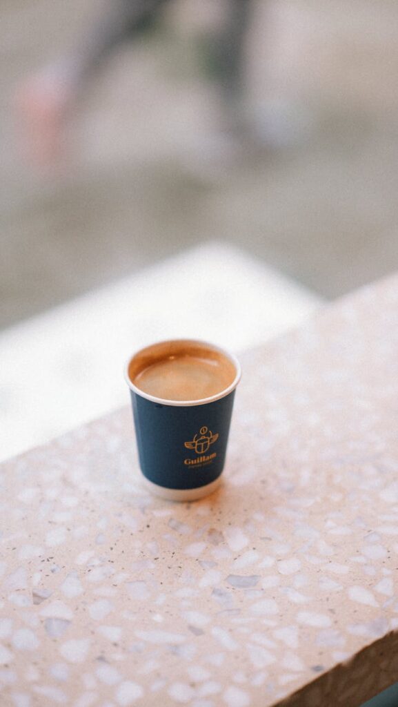 single espresso in a blue paper cup on terrazzo